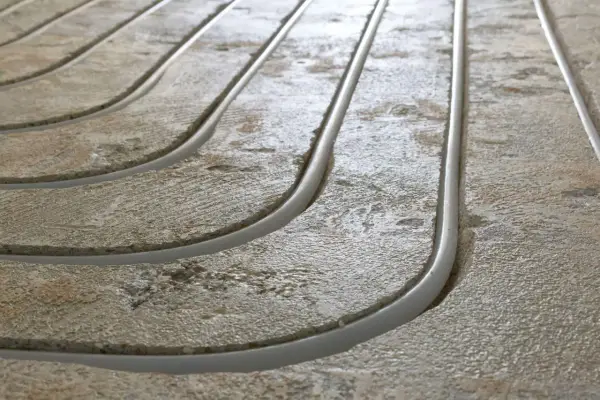Frezowanie pod podłogówkę: betonowe rowki z rurkami grzewczymi, gotowe do zalania.