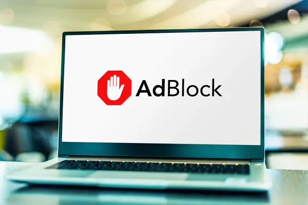 Laptop z logo AdBlock. Dowiedz się, jak wyłączyć adblocka, aby zobaczyć treści.