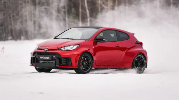 Czerwony Toyota GR Yaris driftuje po śniegu, tworząc obłoki białego puchu.
