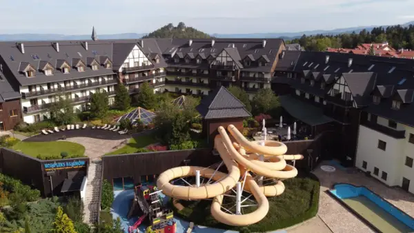 Karpacz hotel z aquaparkiem oferuje zjeżdżalnie i baseny. Widać też góry w tle.