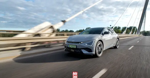 Szary Kia EV6 jedzie po moście w słoneczny dzień.