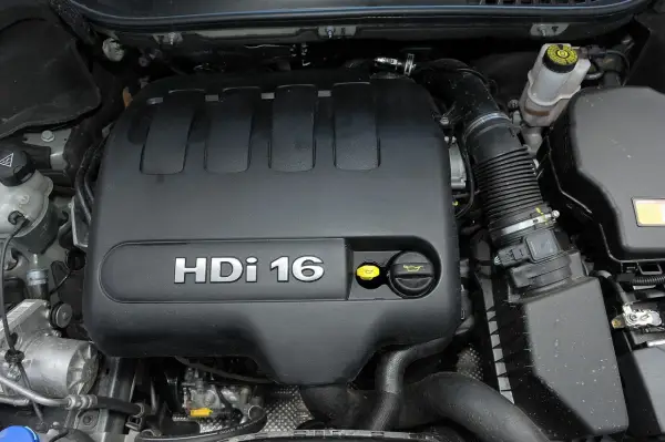 Silnik 2.0 HDi w Peugeot Expert. Widoczny czarny plastikowy dekiel z napisem HDi 16, żółty korek oleju i inne elementy komory silnika.