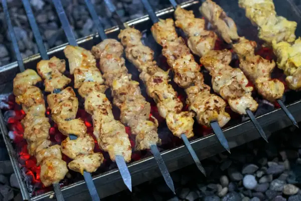 Kebab w domu na węglu, soczyste kawałki mięsa pieką się na szpikulcach, kusząc aromatem.
