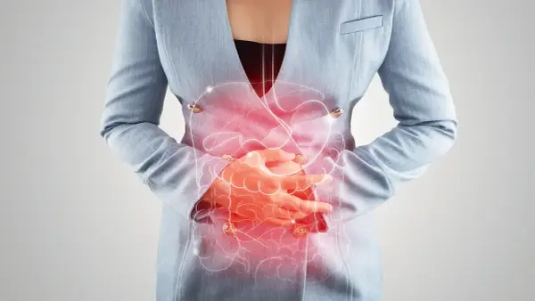 Frau hält sich den schmerzenden Bauch, rote Darstellung des Verdauungstrakts. Mögliche bauchfellentzündung symptome.