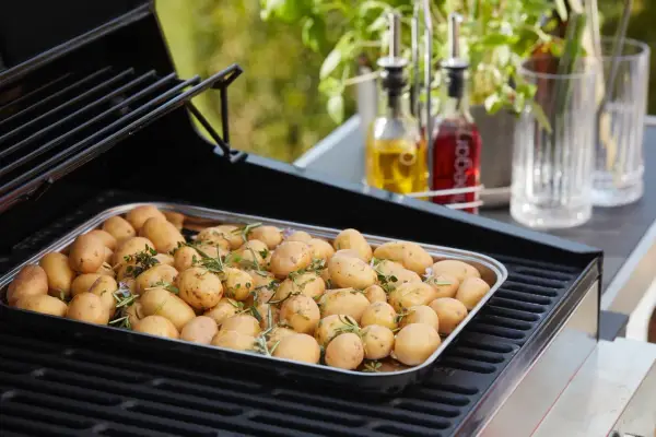 Un plateau de pommes de terre nouvelles assaisonnées d'herbes, prêtes pour le barbecue.