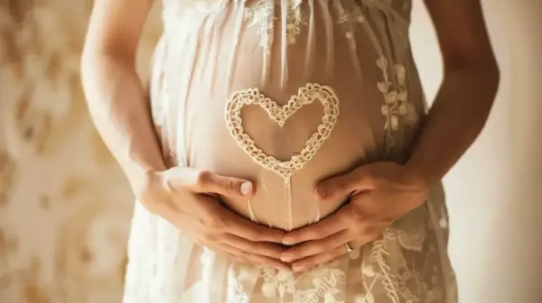 Brzuszek w 7 tygodniu ciąży, otulony koronkowym sercem. Dłonie mamy i taty czule obejmują przyszłe życie.