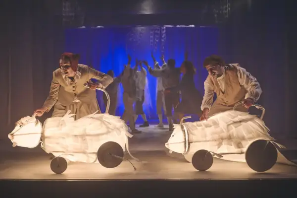 Aktorzy Teatru Lalki i Aktora Wałbrzych prowadzą świetliste, papierowe zwierzęta na scenie.
