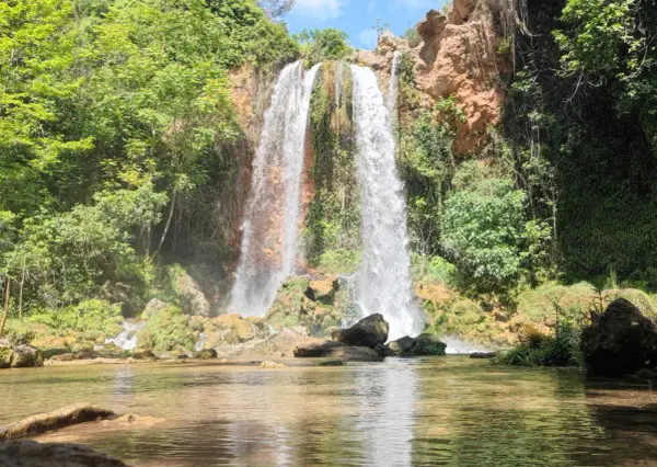 Cascada imponente cayendo en el lago de Anna, rodeada de vegetación exuberante y rocas cubiertas de musgo.