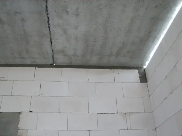 Betonowy strop z widocznym pęknięciem nad ścianą z białych pustaków.