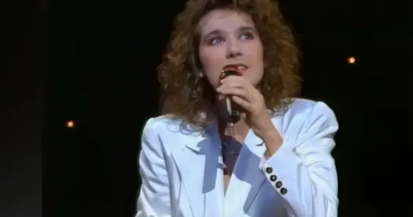 Celine Dion w białej marynarce śpiewa do mikrofonu, przypominając jej występ na Eurowizji.