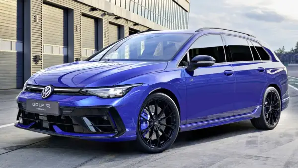 Niebieskie kombi auto Volkswagen Golf R Variant z czarnymi felgami i niebieskimi zaciskami hamulcowymi stoi przed nowoczesnym budynkiem.
