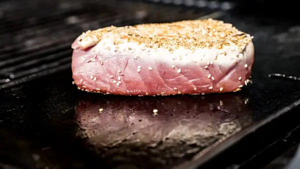 Surowy stek z tuńczyka w sezamie na rozgrzanym grillu.