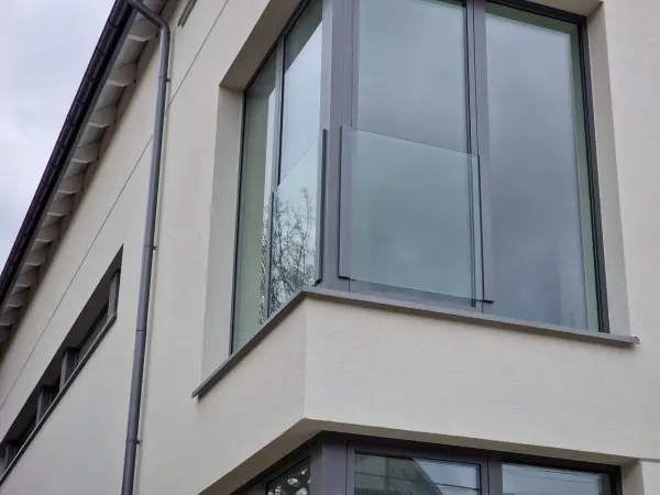 Nowoczesne portfenetry z przeszklonymi balustradami na jasnej elewacji.