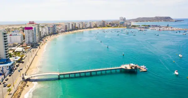 Malecón w Manta, Ekwador. Widok na plażę, budynki, molo i zatokę z łodziami. Tu właśnie leży Ekwador, kraj na równiku.