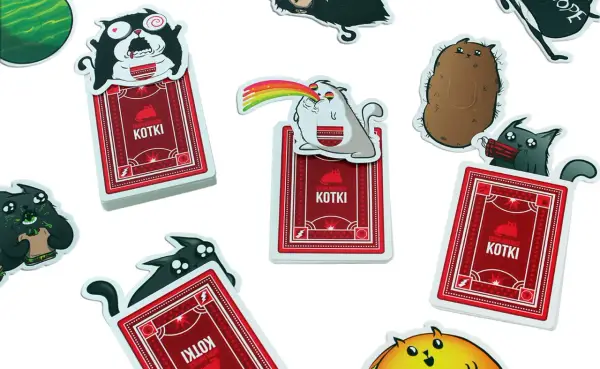 Karty z gry "Eksplodujące Kotki: Imprezka" przedstawiają szalone koty, jeden z tęczą z pyska, inny z dynamitem.