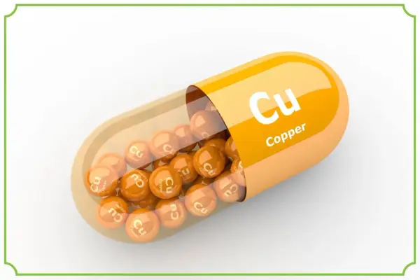Pomarańczowa kapsułka z wysypującymi się z niej kulkami z napisem "Cu Copper". Suplement diety.