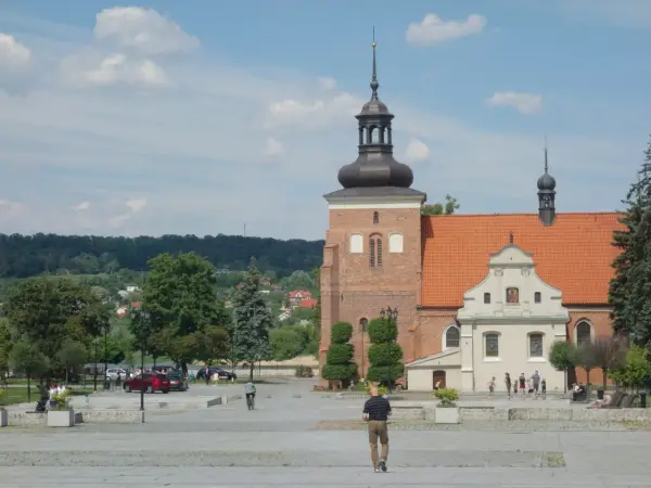 Włocławek atrakcje na weekend: plac z katedrą, spacerowicze, drzewa i zielone wzgórza w tle.