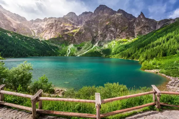 Turkusowe jezioro otoczone zielonymi zboczami gór i lasem, przypominające beskidzkie Morskie Oko.