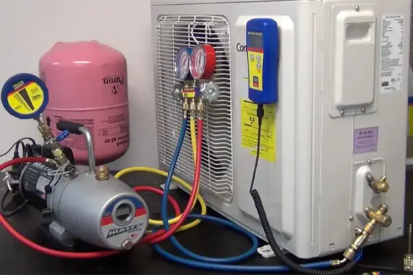Equipo para hacer vacío a un aire acondicionado: bomba, manómetros, tanque de refrigerante y mangueras.