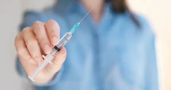 Dłoń trzyma strzykawkę z lekiem, być może Trulicity, gotową do podania.