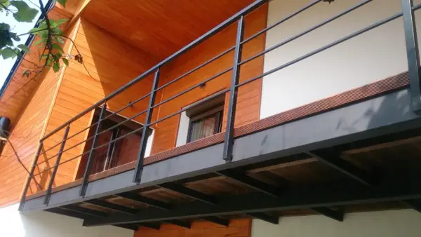Nowoczesna balkon konstrukcja z czarną balustradą i drewnianymi elementami domu.