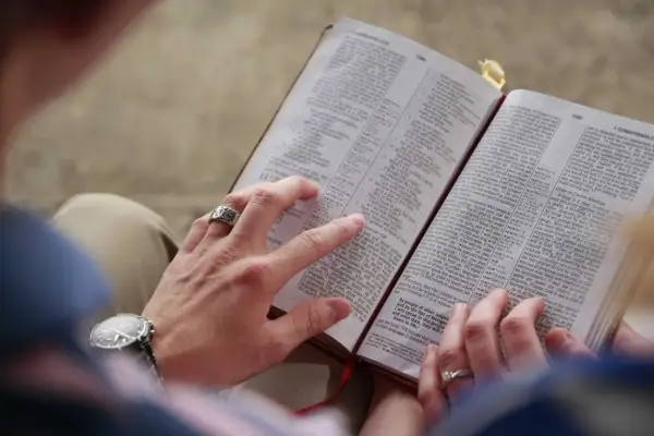 Dłonie pary przeglądają Biblię, szukając pocieszenia i siły przeciwko złemu duchowi.