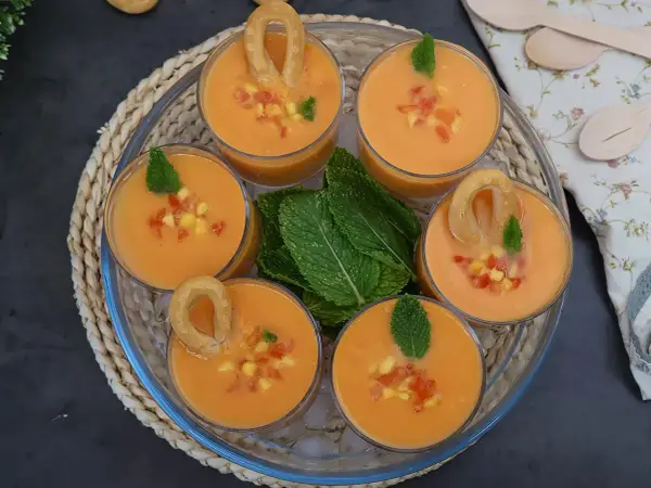 Gazpacho de mango en vasos con trocitos de mango, menta y picos.