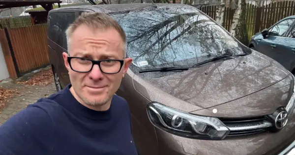 Mężczyzna w okularach przed brązowym vanem, gotowy do podpisania umowy komisu.