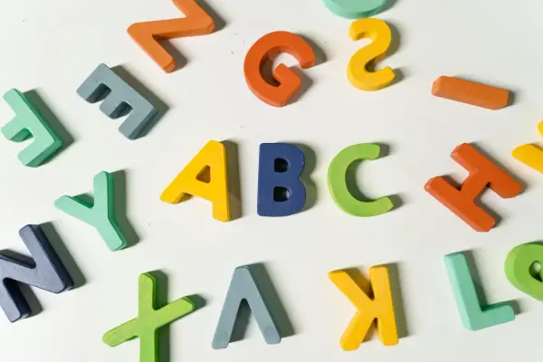 Kolorowe drewniane litery, idealne dla nauczyciela wychowania przedszkolnego, tworzą napis "ABC" i inne znaki.