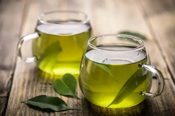 Dos tazas de té verde en vasos de cristal, con hojas flotando. Descubre para qué sirve el té verde y sus beneficios.