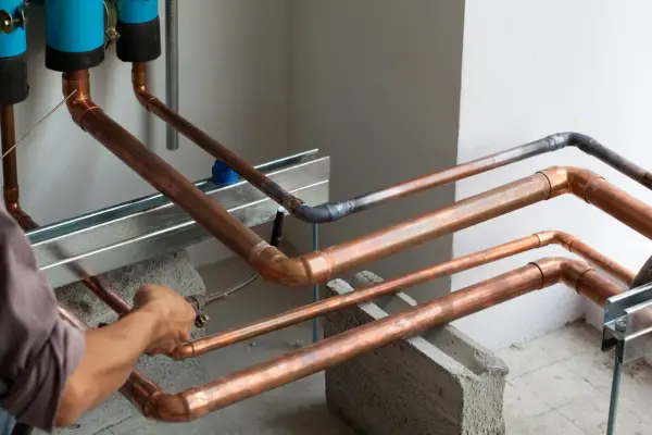 Instalator lutuje miedziane rury. W tle widać niebieskie filtry.