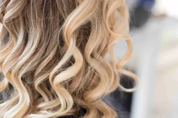 Piękne, falowane włosy z subtelnym balejażem blond, dodającym im blasku i głębi.