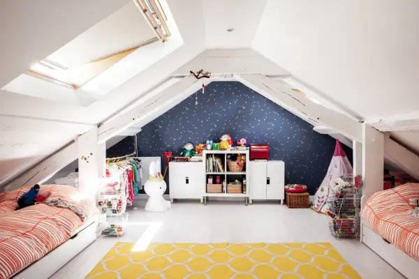 Kreative kinderzimmer dachboden ideen: zwei Betten, Spielzeug, Kleiderständer und ein Sternenhimmel an der Wand schaffen eine gemütliche Atmosphäre.