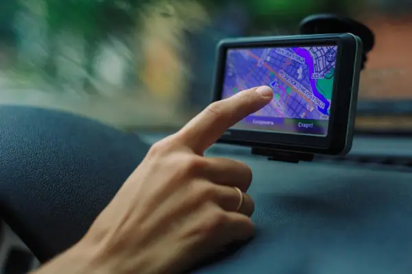 Palec dotyka ekranu nawigacji, uruchamiając mydrive connect. Widok z samochodu na mapę.