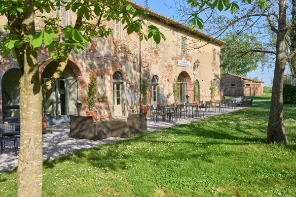 Antica locanda nel Val di Chiana, con tavoli all'aperto e un prato fiorito.