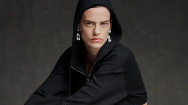 Modelo con sudadera negra con capucha y pendientes de lágrima, una visión audaz que evoca la estética de Pierpaolo Piccioli.