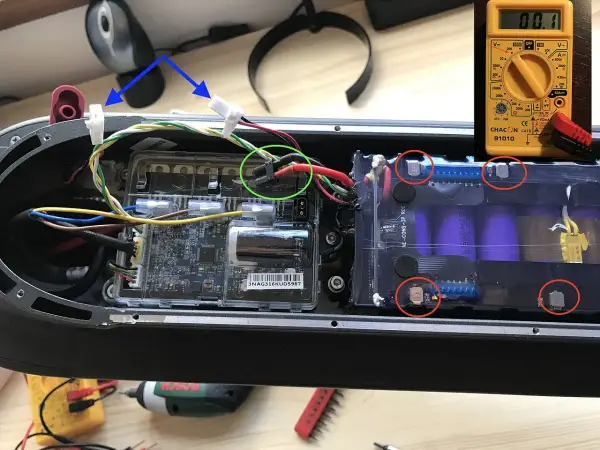 Le fusible de la trottinette électrique est ici, près des connexions de la batterie. Un multimètre est visible.