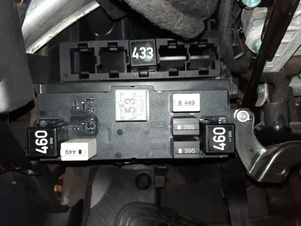 Skrzynka bezpieczników w Audi A3 8P. Widoczne przekaźniki i bezpieczniki, m.in. z oznaczeniami 460, 433, 395. Opis bezpieczników jest kluczowy.