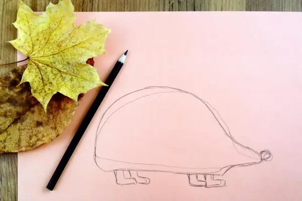 Ołówek i jesienne liście obok szkicu jeża. Zobacz, jak narysować jeża krok po kroku!
