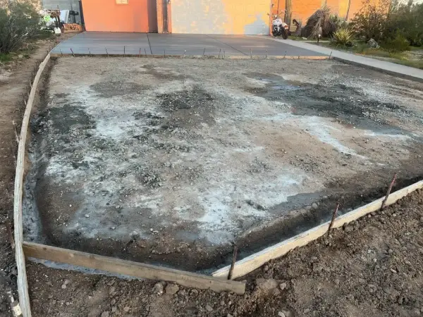 Plac budowy podjazdu z kamienia. Widać szalunki i przygotowany teren pod wylanie betonu.