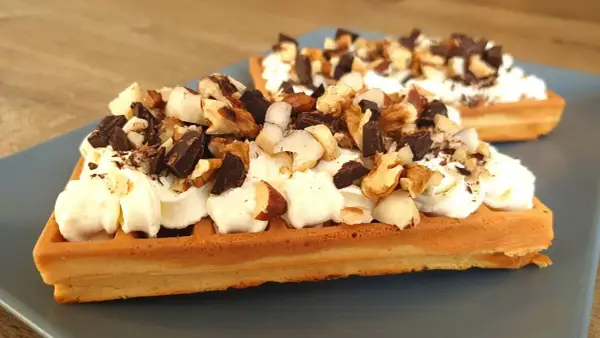 Dwa keto gofry z mascarpone, udekorowane kawałkami czekolady i orzechów. Idealne na deser.
