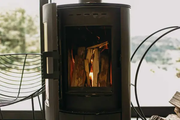 Poêle à bois allumé, avec une prise d'air poele à bois obligatoire pour une combustion optimale. Le feu crépite joyeusement.
