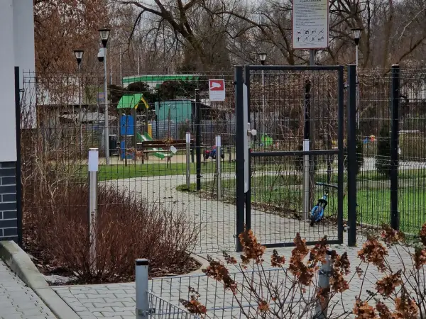 Prawda o ustawie która ma zakazać grodzenia osiedli w dużych miastach: ogrodzony plac zabaw z bramą i tablicą informacyjną.