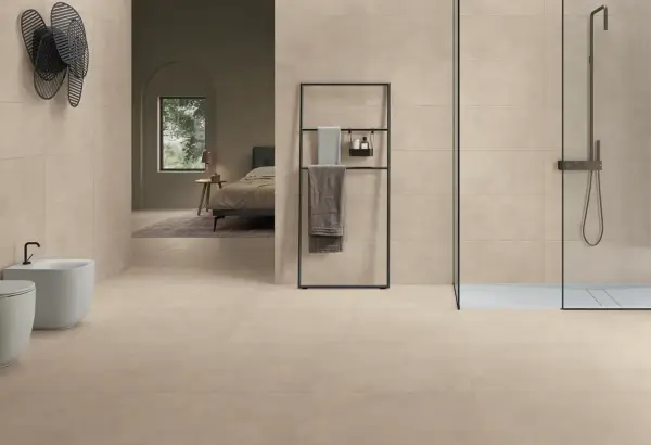 Salle de bain moderne avec bidet, douche et lit visible au loin, le tout revêtu de grès cérame émaillé.