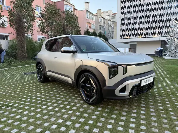 El ev2 kia, un SUV eléctrico plateado, descansa sobre un césped con baldosas cuadradas.