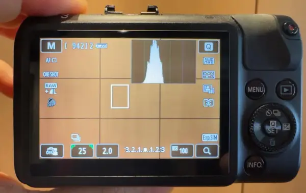 Schermo di una fotocamera **Canon M** in modalità manuale, con istogramma e impostazioni visibili.