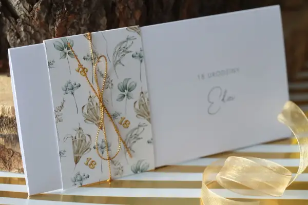 Eleganckie zaproszenia na 18 urodziny z motywem roślinnym i złotym sznurkiem. Idealne, by pokazać, jak spersonalizować zaproszenia na osiemnastkę diy pomysły i materiały.