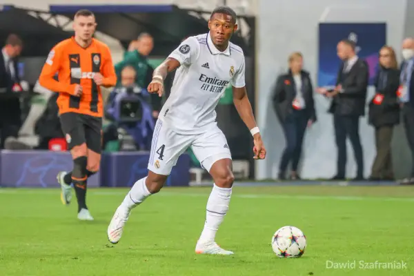 Piłkarz Realu Madryt w białej koszulce z numerem 4, David Alaba, prowadzi piłkę. W tle widać zawodnika Szachtara Donieck w pomarańczowej koszulce. To obraz jednego z najlepszych obrońców świata.