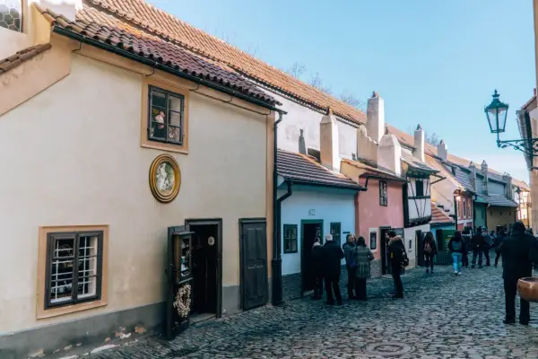 Uliczka Złota w Pradze, z kolorowymi domkami i brukowaną ścieżką, przyciąga turystów.