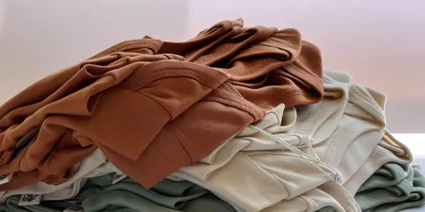 Stapel weicher Stoffe in Erdtönen. Die Falten und Nähte zeigen die Textur, die bei Tencel Nachteile wie Knitteranfälligkeit haben kann.